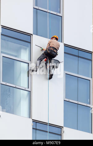 Der Arbeiter hängen an clambing Seil, reinigen Sie die Windows ond Außenhülle des hohes Gebäude. Stockfoto