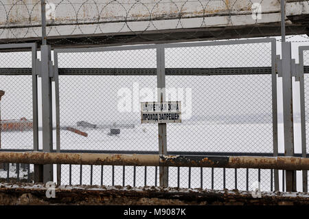 Ein Schild "Verboten. Keine Eingabe" auf dem Zaun von uglitsch Wasserkraftwerk gelegt, gefrorenen Fluss und Schnee bedeckt die Banken sind auf der backgroun Stockfoto