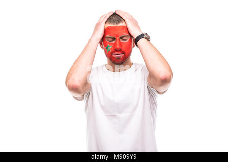 Schöner mann Fan Fan von Marokko Nationalmannschaft bemalte Flagge Gesicht unglücklich, traurig, frustriert emoitions in eine Kamera. Stockfoto