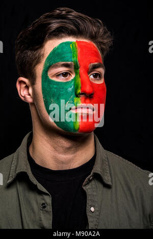 Portrait von stattlicher Mann Gesicht Fan Fan von Portugal Nationalmannschaft mit gemalten Flagge Gesicht auf schwarzen Hintergrund isoliert. Stockfoto