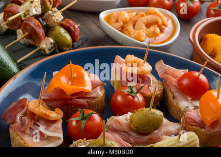 Verschiedene Sandwiches mit Schinken, Paprika und Oliven auf blauen Platte Stockfoto