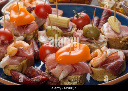 Verschiedene Sandwiches mit Schinken, Paprika und Oliven auf blauen Platte Stockfoto