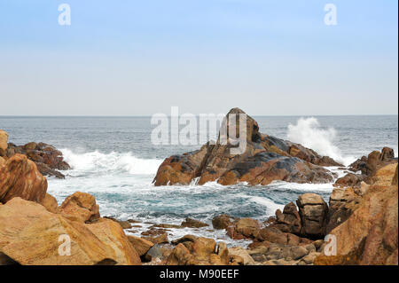 Wellen über Felsen aus rotem Granit brechen, Margaret River Region, West Australia Stockfoto