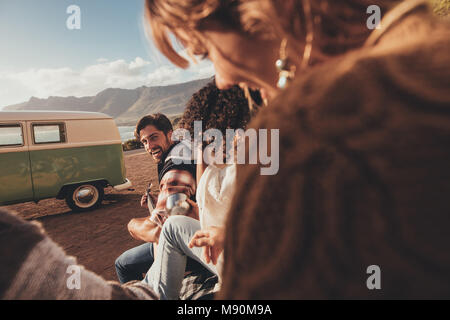 Mann spielt Gitarre für seine Freunde. Eine Gruppe von Freunden auf roadtrip Entspannung im Freien. Stockfoto