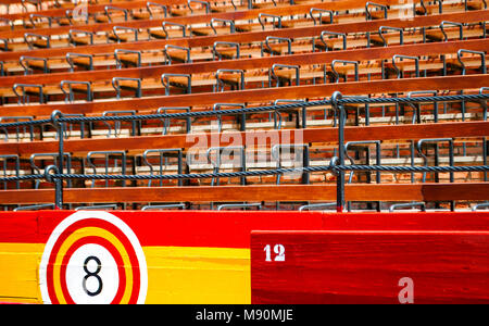Detail der Sitze innerhalb eines alten Spanischen Arena mit Holzsitzen und Barrieren in den Farben der Spanischen Flagge Stockfoto