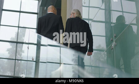 Ansicht der Rückseite des Leitenden Angestellten sprechen während der aufsteigenden Treppen in modernes Bürogebäude Stockfoto