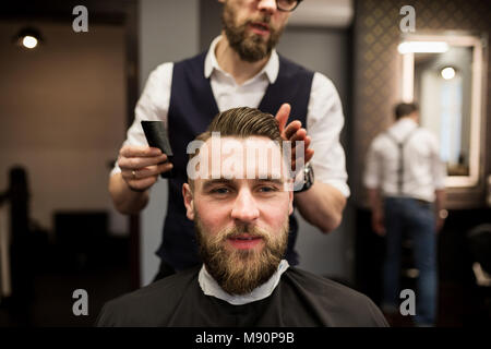 Vordere Portrait von froh, junge Mann in die Haare schneiden bei Friseur Salon Stockfoto