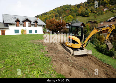Baustelle. Mechanische Bagger bei der Arbeit in einem Garten. Stockfoto