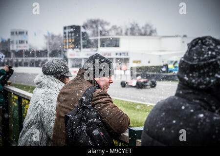 Zuschauer einfrieren im Schnee beobachten die Formel 5000 Demonstration des Antriebs beim Goodwood Mitgliederversammlung 76 MM in Goodwood Motor Circuit Stockfoto