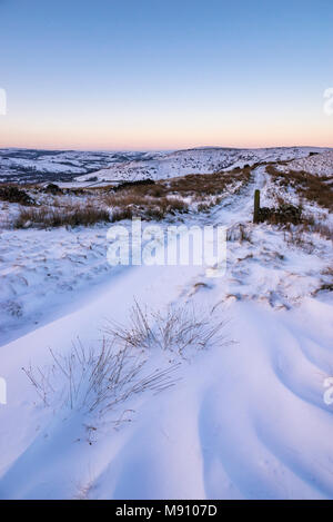 Tiefe Schneeverwehungen neben dem Reitweg in South Head, Hayfield im Peak District, Derbyshire, England. Stockfoto