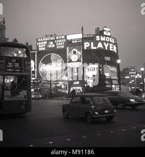 1960, historische Bild von London Piccadilly Circus am Abend mit Fahrzeugen und dem berühmten Neonlicht Werbetafeln für Marken wie "Spieler Zigaretten' und 'Coca-cola'. Stockfoto