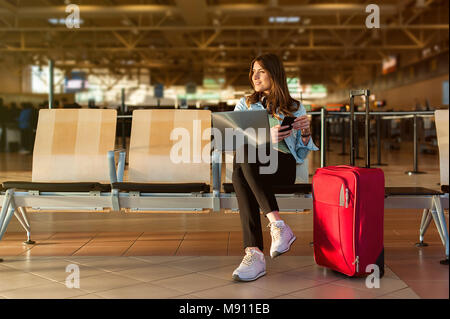 Flughafen jungen weiblichen Passagier auf Smartphone und Laptop im Terminal Hall beim Warten auf ihren Flug Stockfoto