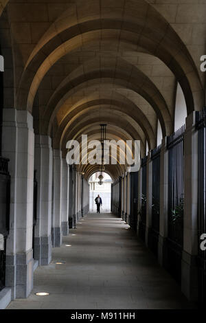 Ein Mann unter den Arkaden im Savoy Place, London. Stockfoto