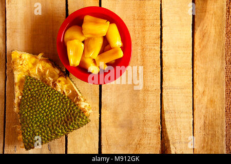 Blick von oben auf die rote Schale mit jackfruit Hülsen und jackfruit Haut auf Holz- Hintergrund isoliert Stockfoto