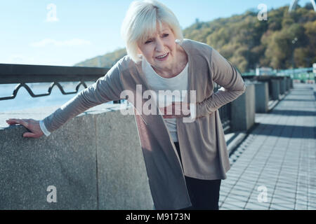 Pensionierte Dame Verdoppelung durch starke Schmerzen Stockfoto