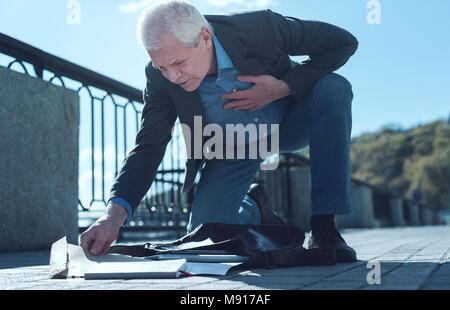 Älterer Mann mit schweren Herz Schmerz aufnehmen Dokumente Stockfoto