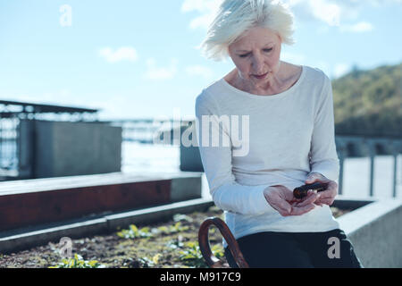 Verärgert Ruhestand Dame, die Pillen im Freien Stockfoto