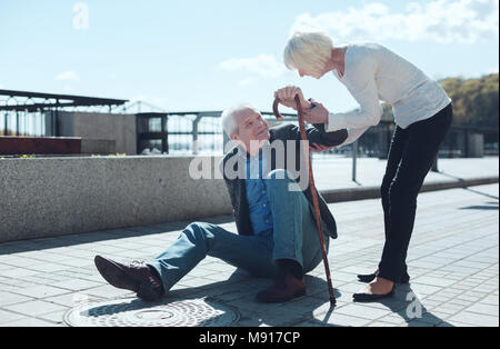 Liebevolle Frau helfen älteren Mann oben zu stehen Stockfoto