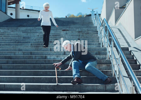 Verängstigte Frau zu Mann liegen auf Treppen laufen Stockfoto