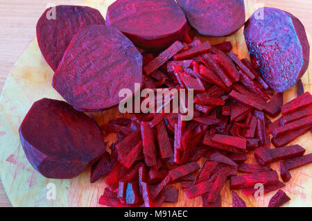 Rote Bete in Scheiben geschnittene Streifen, Zuckerrüben gehackt Hälften, rohe rote Beete zum Kochen Stockfoto