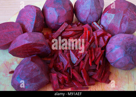 Rote Bete in Scheiben geschnittene Streifen, Zuckerrüben gehackt Hälften, rohe rote Beete zum Kochen Stockfoto