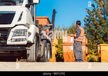 Arbeiter auf der Baustelle entladen Container für Abfälle aus Lkw Stockfoto