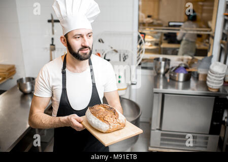 Bäcker mit Brot in der Bäckerei Stockfoto