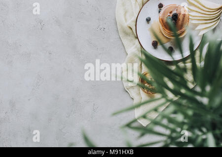 Selektiver Fokus der leckere hausgemachte Pfannkuchen mit Honig und Beeren auf Grau Stockfoto