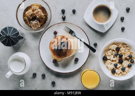 Blick von oben auf die lecker gesundes Frühstück mit Pfannkuchen und Müsli auf Grau Stockfoto