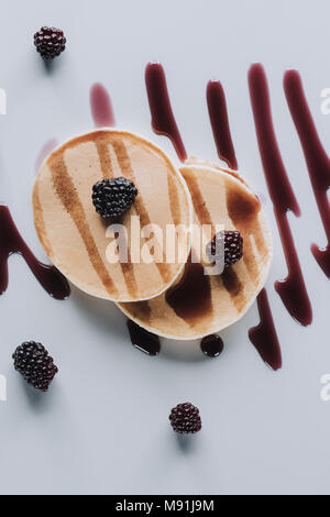 Blick von oben auf die Süße Pfannkuchen mit frischen Brombeeren und Marmelade auf Grau Stockfoto