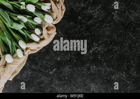 Blick von oben auf die White Tulip Blumen auf Tischdecke auf schwarze Oberfläche Stockfoto