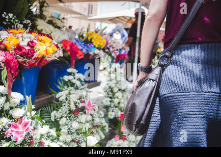 Frau geht vorbei an bunten exotischen Blumen auf Verkauf in Blumentöpfe in einem Blumenmarkt in Cuenca, Ecuador Stockfoto