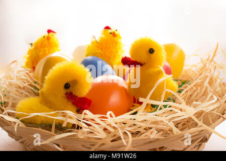 Ostern Dekorationen. Im Weidenkorb sind Stroh und Hühner Hühner Enten und bunte Eier. Stockfoto