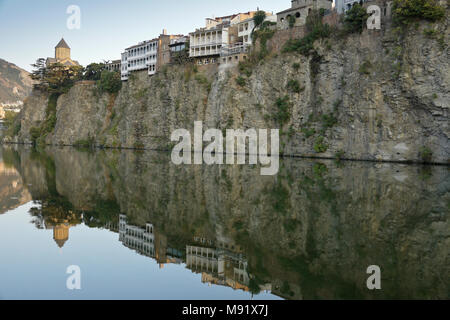 Metekhi Kirche und Gebäude mit Balkonen, auf einer felsigen Klippe sind in den stillen Wassern des Mtkvari (Kura) Fluss, Tiflis, Georgien reflektiert Stockfoto