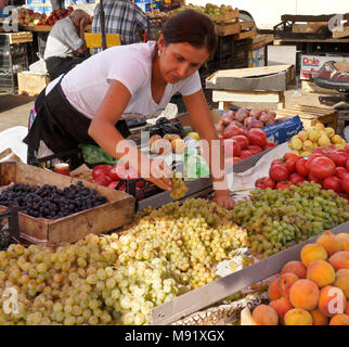 Eine Frau, die den Verkauf von frischen Produkten, einschließlich Trauben, Pfirsiche und Tomaten, räumt ihr Display an der Dezerters" Basar Open-Air-Markt, Tiflis, Georgien Stockfoto