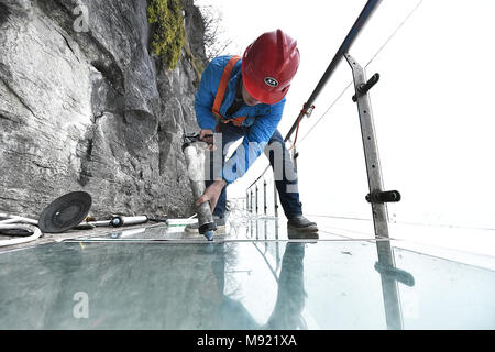 Zhangjiajie, Hunan Provinz Chinas. 21 Mär, 2018. Ein Arbeitnehmer, der Dichtungen der Gemeinsamen von Glasplatten auf dem Glas Fahrbahn in Tianmenshan Scenic Area in Granby, Chinas Provinz Hunan, 21. März 2018. Austausch des Glases Bürgersteig auf der Westseite in Tianmenshan ist in Bearbeitung, die voraussichtlich in zwei Tagen abzuschließen. Credit: Shao Ying/Xinhua/Alamy leben Nachrichten Stockfoto