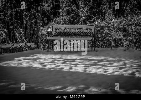 Gartenbank im Winter Schnee, Schwarz und Weiß. Gartenbank im frisch gefallenen Schnee, morgen leuchtet. Stockfoto