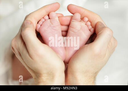 Neugeborenes Baby - Füße in Vaters Hand Stockfoto