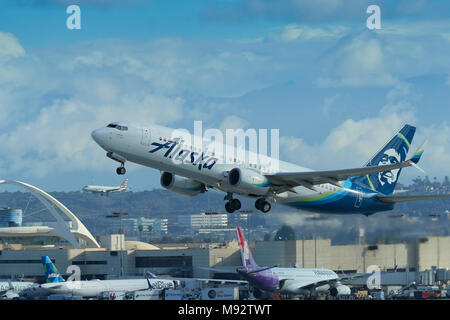 Alaska Airlines Boeing 737-800 Zieht aus Los Angeles International Airport LAX. Eine Landing Jet Airliner im Hintergrund. Kalifornien, USA. Stockfoto