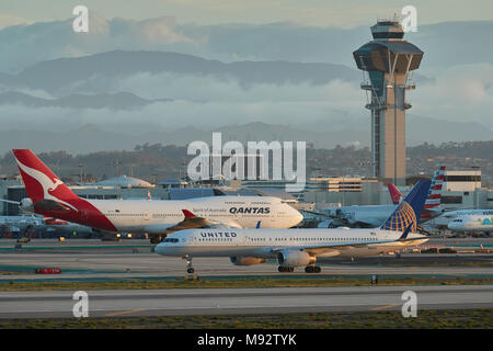 Am frühen Morgen am internationalen Flughafen von Los Angeles, LAX, ein United Airlines Boeing 757 und Qantas Boeing 747-400, mit der Control Tower hinter. Stockfoto