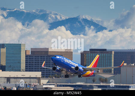 Southwest Airlines Boeing 737 Airliner vom Internationalen Flughafen Los Angeles, LAX, Wolken und Schnee bedeckten San Gabriel Berge dahinter. Stockfoto