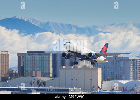 Delta Air Lines Airbus A319 Airliner vom Internationalen Flughafen Los Angeles, LAX, Wolken und die schneebedeckten San Gabriel Berge dahinter. Stockfoto