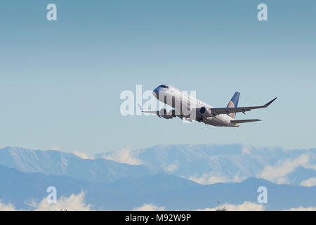 United Express, SkyWest, Embraer E-175 E-Jet, vom internationalen Flughafen Los Angeles, LAX, die schneebedeckten San Gabriel Berge dahinter. Stockfoto