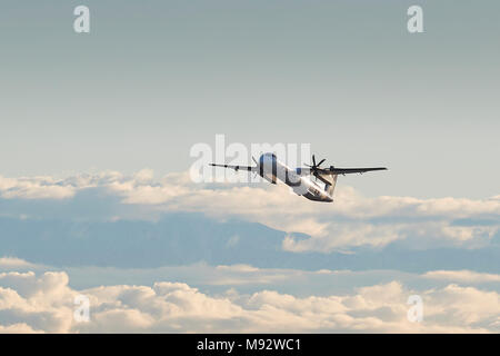 Horizon Air Bombardier Dash-8-Q400 In Alaska Airlines Livree, Klettern aus Los Angeles. Wolken über die Stadt und die schneebedeckten San Gabriel Mountains Stockfoto