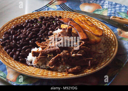 Traditionelle venezolanischen Gericht Pabellon Criollo. Weißer Reis, zerfetzt, Rindfleisch, schwarze Bohnen, gebratene Bananen essen. Mittagessen Zeit. Stockfoto