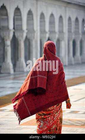 Gurudwara Bangla Sahib, Delhi: Lokale Frau tragen traditionelle Kleidung, wandern durch gewölbte Fassade der Gebäude hinter Stockfoto