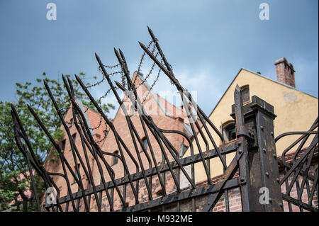 Sicherheit Maßnahmen um eine Detention Center Komplex in Torun, Polen. Stacheldraht, hohen Zaun, gezackten Spitzen gegen den blauen Himmel Hintergrund Stockfoto