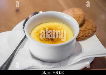 Crème Brûlée, auch als Gebrannte Creme bekannt, ein Dessert mit reichen Vanillepuddingunterseite und von Karamell auf Platte gekrönt, mit Cookies Stockfoto