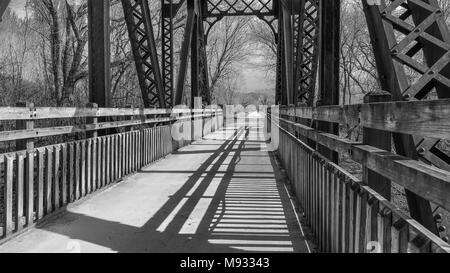 Blick auf eine alte Eisenbahnbrücke umgewandelt in einen Park Trail am späten Nachmittag in Schwarz und Weiß, lange Schatten auf der rechten Seite, Missouri, Mittelwesten Stockfoto