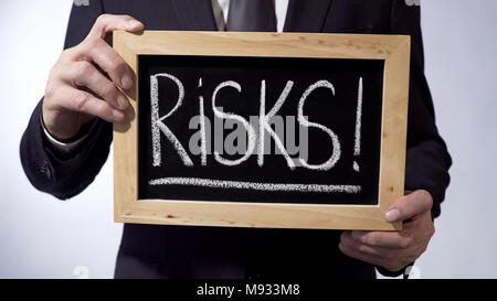 Risiken mit Ausrufezeichen auf Tafel geschrieben, Business person Holding unterzeichnen Stockfoto